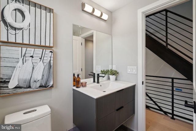 half bath featuring vanity, toilet, and wood finished floors