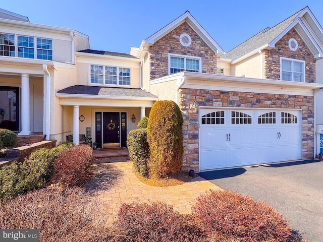 view of front of property with stone siding, covered porch, driveway, and stucco siding