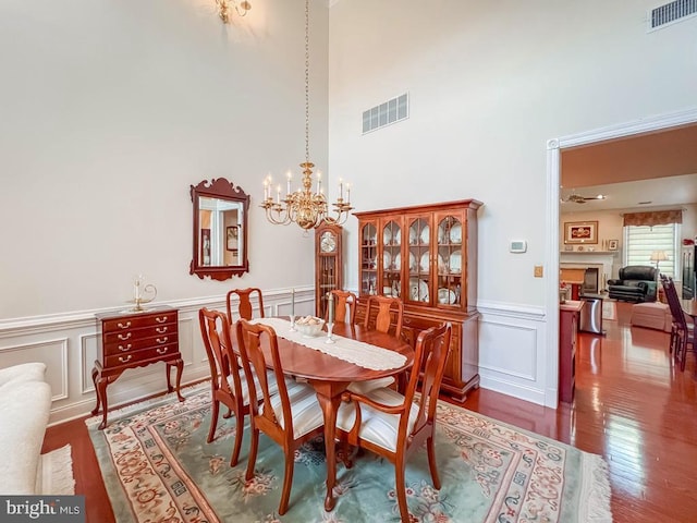 dining room with visible vents, dark wood finished floors, a fireplace, and an inviting chandelier