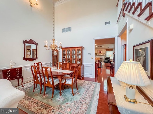 dining room featuring wainscoting, visible vents, a notable chandelier, and wood finished floors