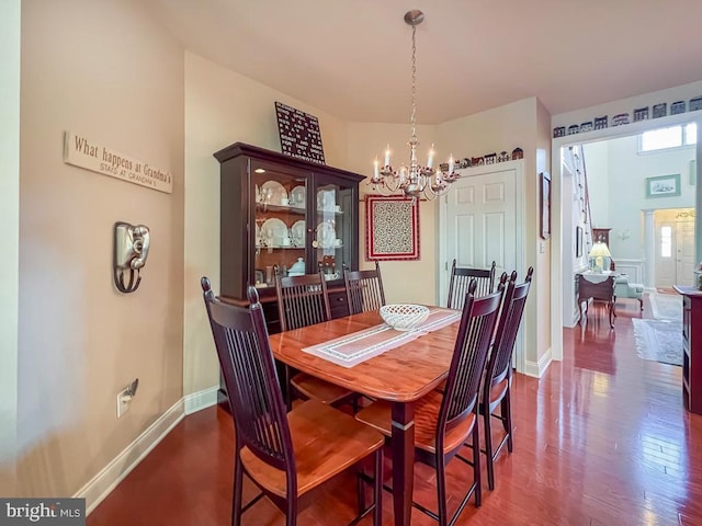 dining area featuring dark wood-style floors, baseboards, and a notable chandelier