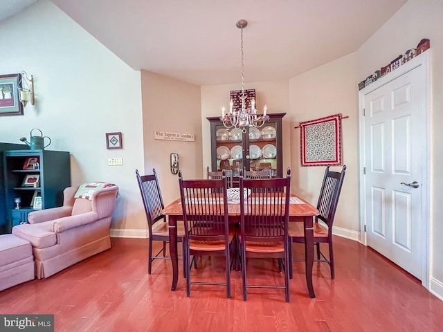 dining space with a notable chandelier, baseboards, and wood finished floors