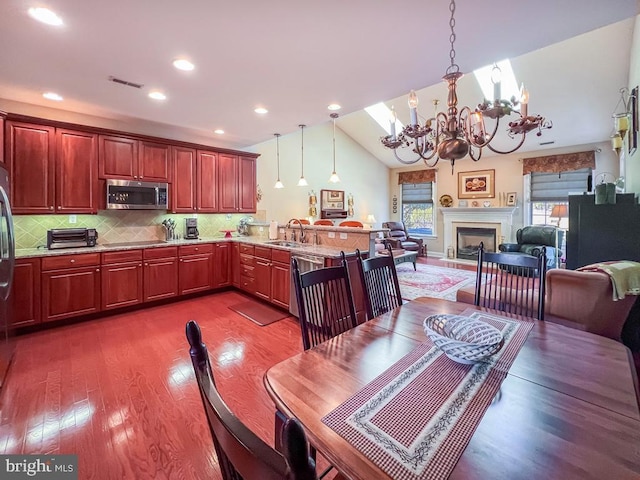 kitchen featuring visible vents, open floor plan, hanging light fixtures, stainless steel appliances, and a sink