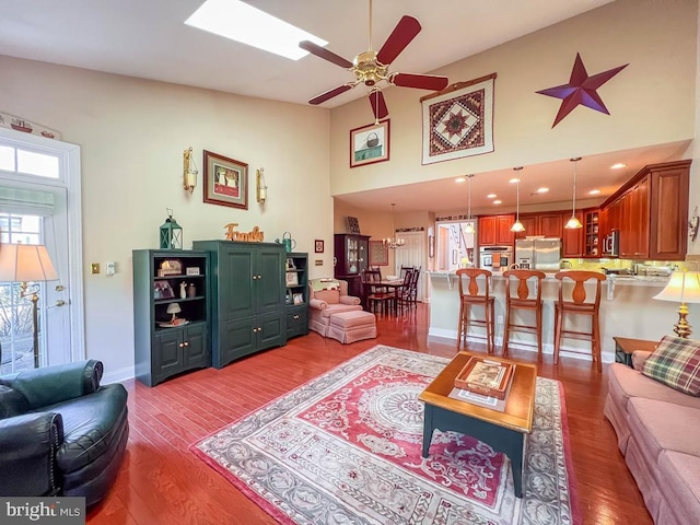 living area featuring ceiling fan, recessed lighting, a skylight, wood finished floors, and baseboards