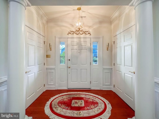 entrance foyer with ornamental molding, dark wood-type flooring, wainscoting, and a decorative wall