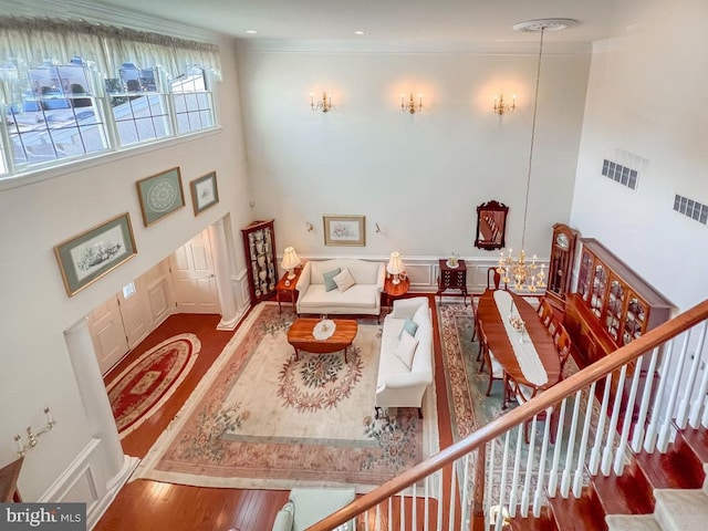 living room featuring visible vents, crown molding, stairway, and a high ceiling