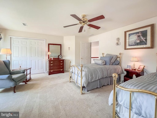 bedroom with ceiling fan, a closet, visible vents, and light colored carpet