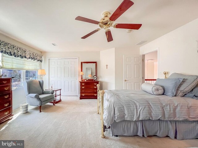 bedroom featuring a closet, visible vents, ceiling fan, and light carpet