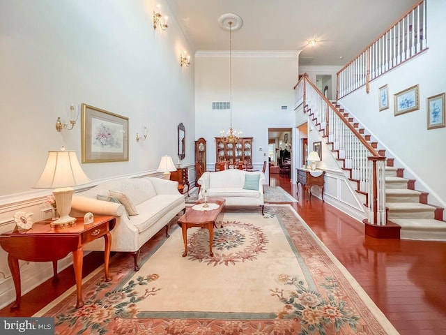 living room featuring ornamental molding, wood finished floors, a towering ceiling, and stairs