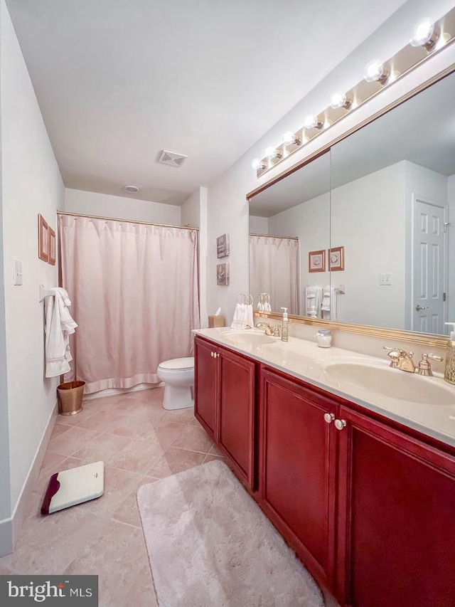 bathroom with toilet, double vanity, a sink, and visible vents