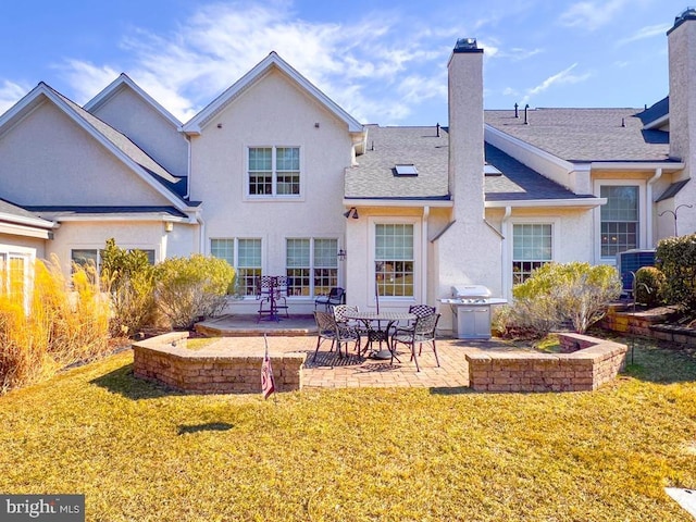 rear view of house featuring a patio area, a chimney, a lawn, and stucco siding