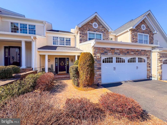 view of front of house featuring aphalt driveway, stone siding, a garage, and stucco siding