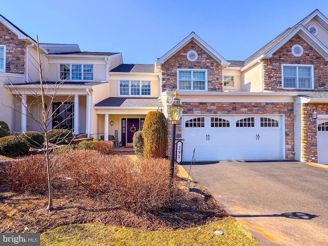 view of front of home with stone siding, aphalt driveway, an attached garage, and stucco siding