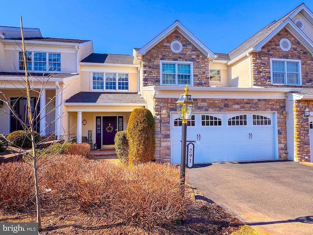 view of front of house with driveway, stone siding, a garage, and stucco siding