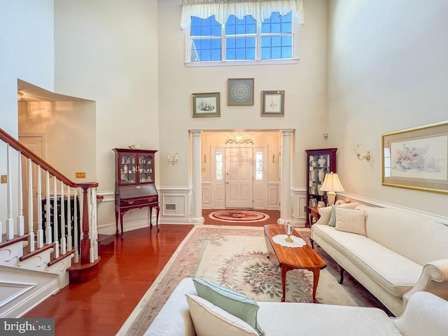 living area with a decorative wall, stairway, a high ceiling, and wood finished floors