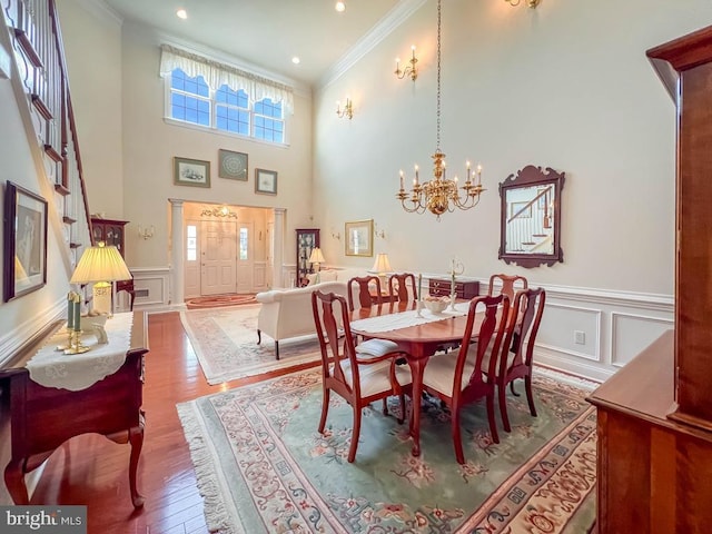 dining space featuring crown molding, a decorative wall, an inviting chandelier, and wood finished floors