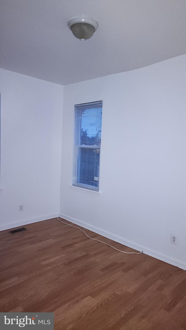 unfurnished room featuring baseboards, visible vents, and dark wood-type flooring