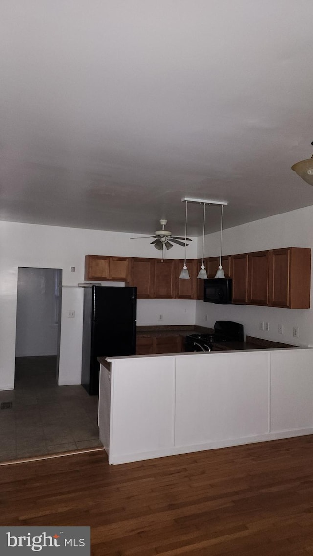 kitchen with brown cabinets, dark wood finished floors, hanging light fixtures, ceiling fan, and black appliances