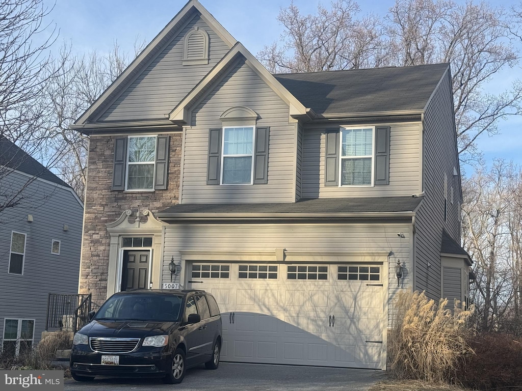 view of front of home featuring a garage, stone siding, and driveway