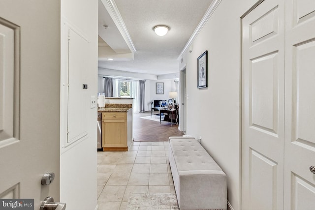 corridor with light tile patterned floors, ornamental molding, and a textured ceiling