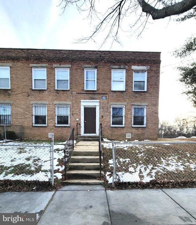 multi unit property featuring a fenced front yard and brick siding