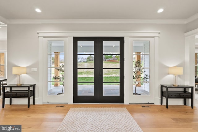 doorway with french doors, light wood-type flooring, and crown molding