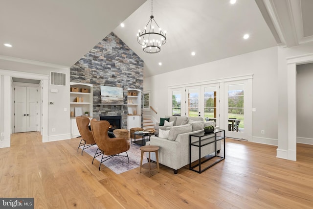 living area featuring light wood finished floors, visible vents, stairs, a fireplace, and high vaulted ceiling