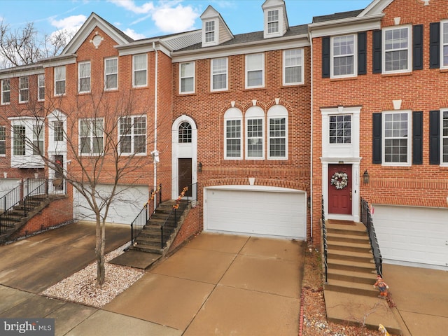 townhome / multi-family property featuring brick siding, driveway, and an attached garage