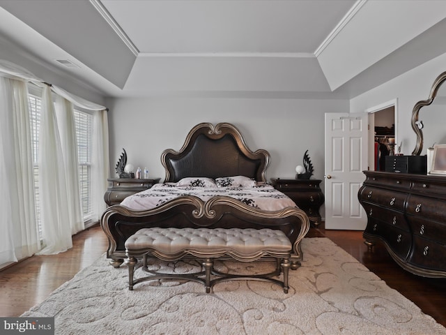 bedroom with ornamental molding, a raised ceiling, visible vents, and dark wood finished floors