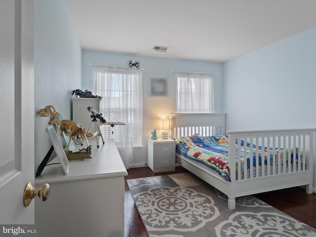 bedroom with dark wood-style flooring, visible vents, and baseboards