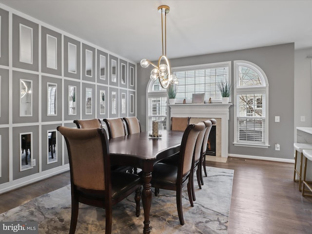 dining space featuring dark wood-style floors, baseboards, a wealth of natural light, and an inviting chandelier