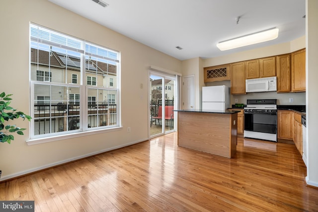 kitchen featuring dark countertops, white appliances, light wood-type flooring, and a wealth of natural light