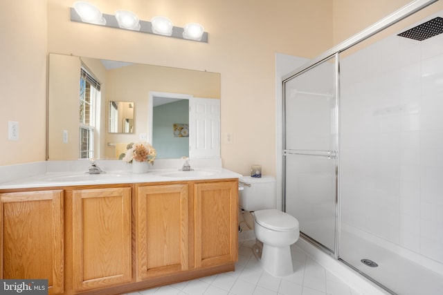 bathroom featuring a stall shower, a sink, toilet, and double vanity