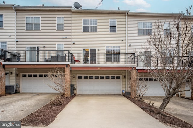 rear view of property featuring driveway, an attached garage, and central AC unit