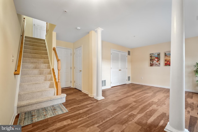 interior space featuring stairs, wood finished floors, decorative columns, and baseboards