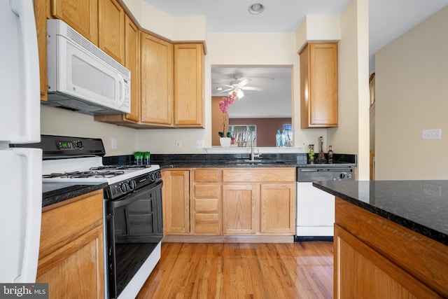 kitchen featuring white appliances, a sink, a ceiling fan, dark stone counters, and light wood finished floors