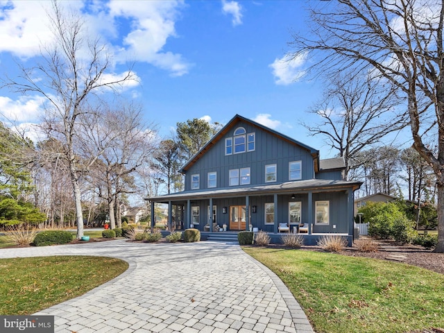 view of front of home featuring a porch, a front yard, decorative driveway, and board and batten siding