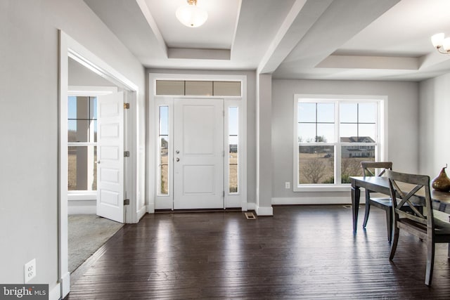 entryway featuring dark wood finished floors, a tray ceiling, and baseboards