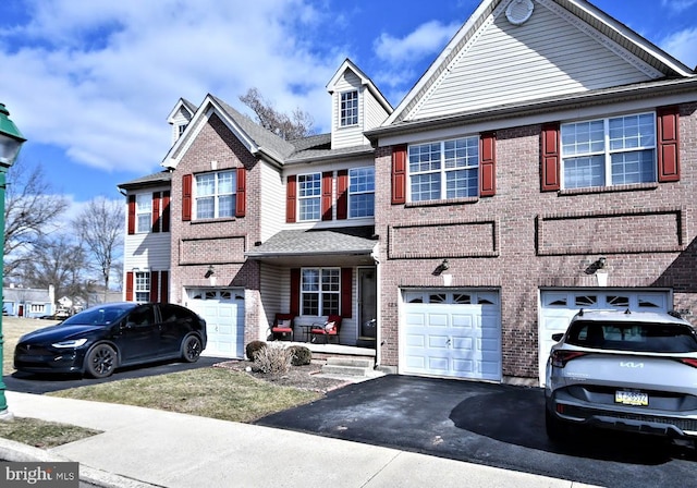 multi unit property with a garage, driveway, and brick siding