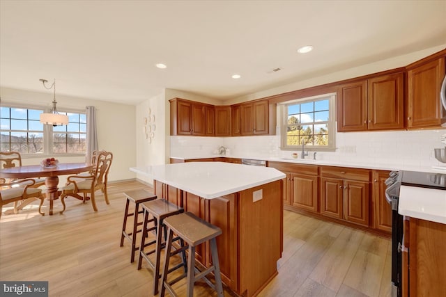 kitchen featuring light countertops, a sink, decorative light fixtures, and stainless steel range with electric cooktop