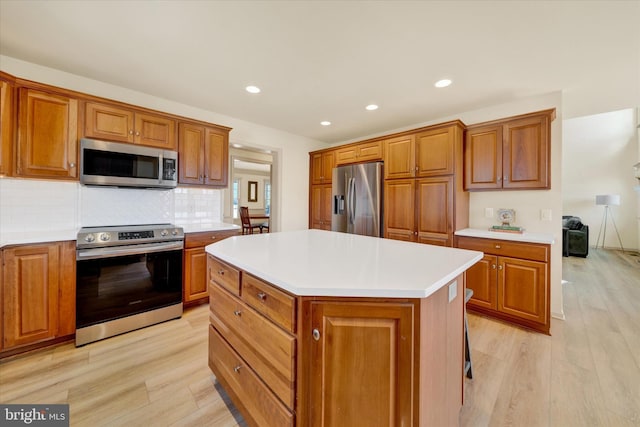 kitchen featuring a center island, brown cabinets, stainless steel appliances, light countertops, and light wood-style flooring