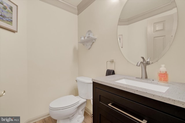 bathroom with toilet, wood finished floors, vanity, baseboards, and ornamental molding