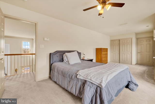 bedroom featuring light carpet, baseboards, visible vents, a ceiling fan, and a closet