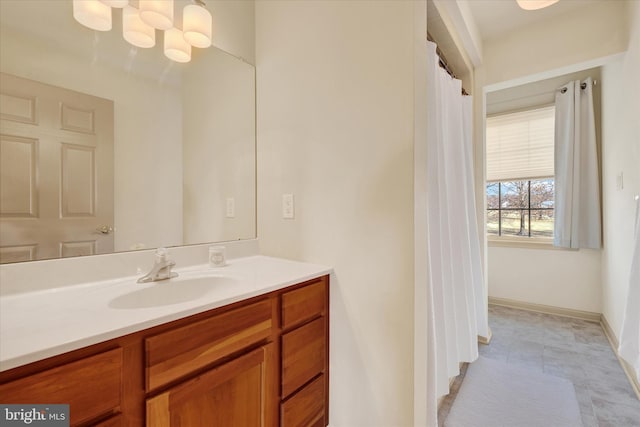 bathroom with a notable chandelier, vanity, and baseboards