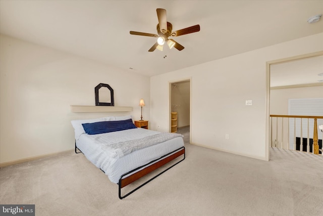 bedroom with light carpet, ceiling fan, a spacious closet, and baseboards