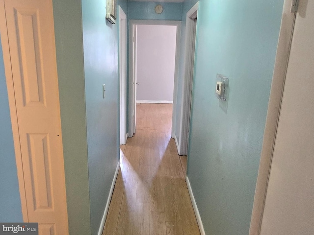 corridor featuring light wood-type flooring and baseboards