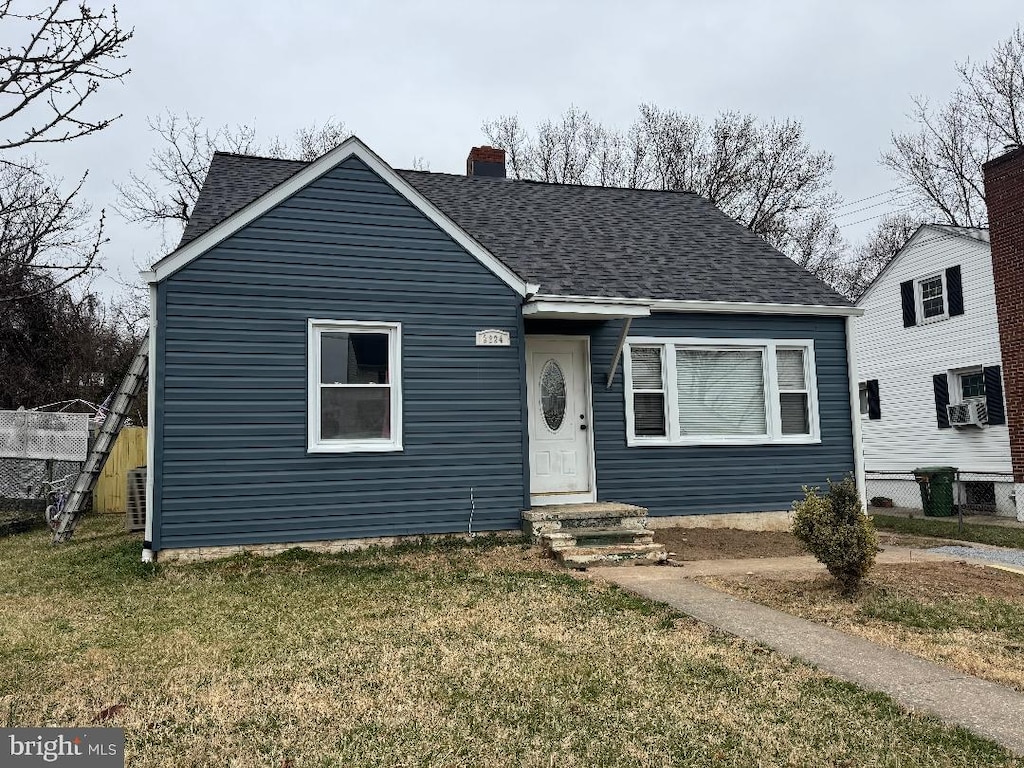 bungalow-style house featuring a chimney, roof with shingles, a front yard, and fence