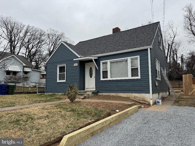 view of front facade with a shingled roof, a chimney, and fence