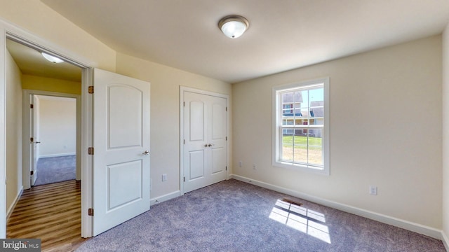 unfurnished bedroom featuring a closet, baseboards, and carpet flooring