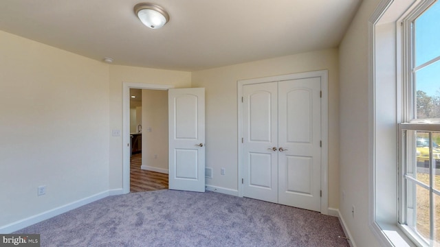 unfurnished bedroom with a closet, light carpet, and baseboards